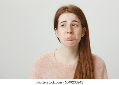 Close-up Shot Of Gloomy And Miserable Redhead Adult With Freckles Whining Or Complaining While Looking Aside, Standing Against Gray Background. Mom I Really Want To Go To That Party, Can I