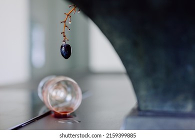 A Closeup Shot Of A Grape And A Spilled Wine On A Table