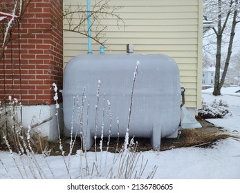 A Closeup Shot Of A Grey Oil Tank Outside Of A Home Surrounded By Snow.