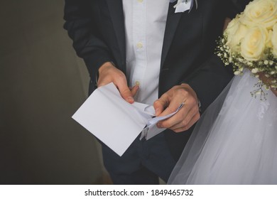 A Closeup Shot Of A Groom Opening An Envelope