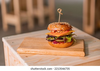 A Closeup Shot Of A Ground Chicken Burger On A Wooden Board On The Table With Blur Background