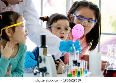 Closeup shot group of Asian little curious elementary schoolgirls wears safety goggles looking observing at water bottle reaction blowing pink rubber balloon experiment teach by science teacher. - Powered by Shutterstock