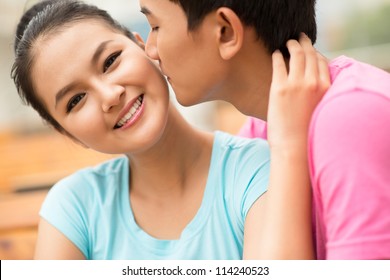 Close-up shot of a guy being about to kiss his girlfriend on the cheek