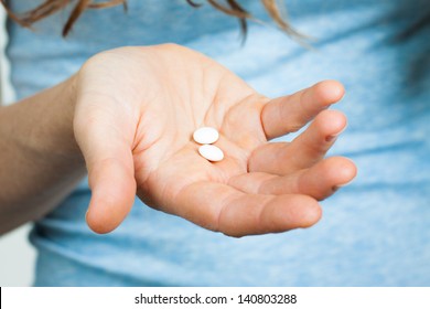 Close-up Shot Of A Hand Holding Two White Pills.