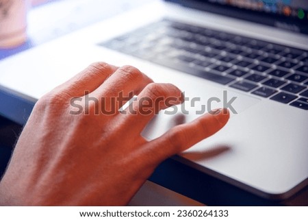 A closeup shot of a hand using the touchpad on the laptop