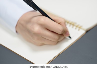 Closeup Shot Of Hand Young Student Lady Freelancer Journalist Writing Article Using Copybook In Gray Modern Home Office. Remote Job, Education And Career Profession Concept. Copy Space