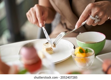 close-up shot of hands of a female asian customer eating desserts at a fining dining restaurant