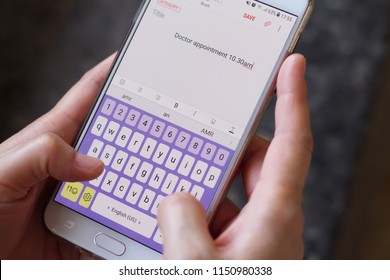 Close-up Shot Of Hands Holding Mobile Phone, And Making A Reminder Of Doctor Appointment Date And Time.