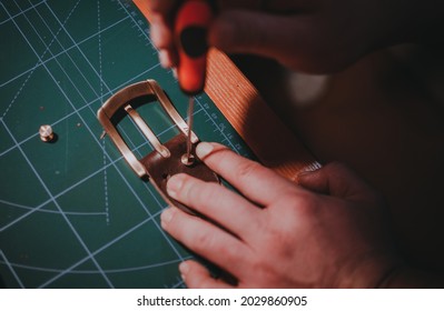 A closeup shot of hands tightening the metal details of the brown leather belt - Powered by Shutterstock