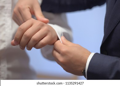 Close-up shot of hands of young Caucasian male being helped with his white shirt sleeve by another elegantly dressed man. Classy groom, stylish businessman, or millennial male model getting ready. - Shutterstock ID 1135291427