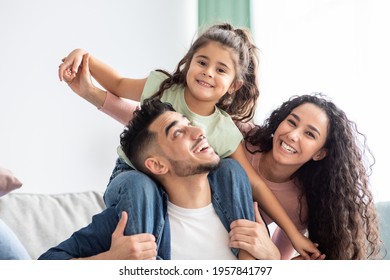 Closeup Shot Of Happy Arab Family Of Three With Little Daughter Having Fun Together At Home, Portrait Of Cheerful Middle Eastern Parents Playing With Their Child In Living Room, Enjoying Weekend - Shutterstock ID 1957841797