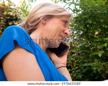 A closeup shot of a happy blonde woman in sunglasses talking via phone