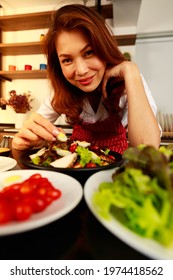 Closeup Shot Of Houswife Hand Decorating Chicken Breast Green Mixed Vegetable Salad With Boiled Egg Yolk On Countertop Desk In Kitchen With Raw Fresh Organic Material In Blurred Foreground.