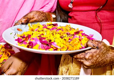 A Closeup Shot Of Indian Woman Holding A Plate With Flower Petals With Henna In Her Hands