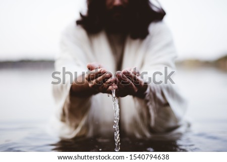 A closeup shot of Jesus Christ holding water with his palms