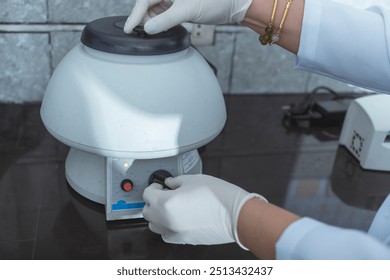 Closeup shot of a laboratory technician operating a tabletop centrifuge. - Powered by Shutterstock