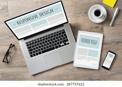 Nahaufnahme eines Laptops mit Digitaltablet und Smartphone auf dem Schreibtisch. Entsprechende Design-Webseite auf ihrem Bildschirm. Moderne Geräte auf dem Schreibtisch im Büro. 
