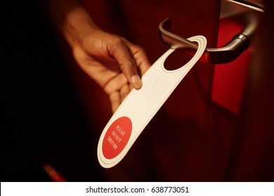 Closeup Shot Of Male Hand Hanging Do Not Disturb Sign On Doorknob Of Hotel Room