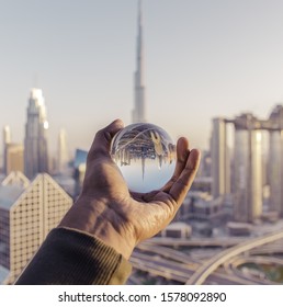 A Closeup Shot Of A Male Hand Holding A Crystal Ball With The Reflection Of The City