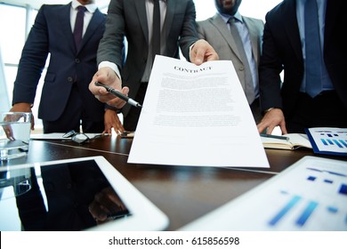 Close-up shot of male hands holding contract and pen and passing them to business partner, table surface with documents and stationery on foreground - Powered by Shutterstock