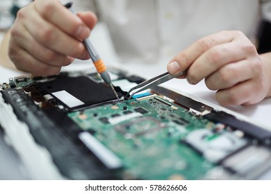 Closeup shot of male hands working on assembling new circuit board using tweezers and screwdriver