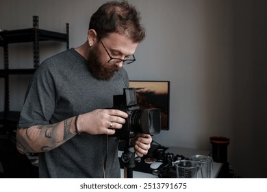 Close-up shot of a male photographer fine-tuning settings on a professional camera mounted on a tripod in a studio setting. - Powered by Shutterstock