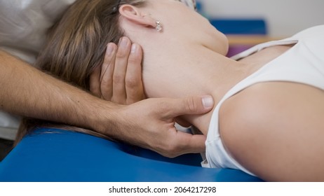 Close-up shot of a male physiotherapist doing manual neck stretching to a young Caucasian female patient. - Powered by Shutterstock