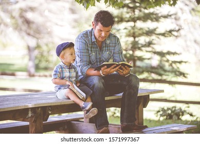 A Closeup Shot Of A Male Reading The Bible For His Child With A Blurred Background