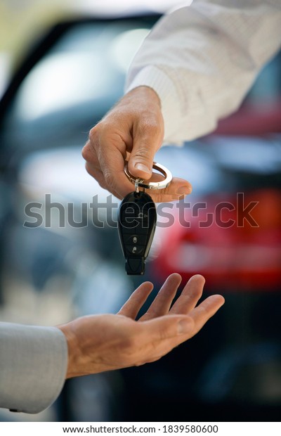 Close-up shot of a man at the car\
dealership getting the keys to his new car from the\
salesman.