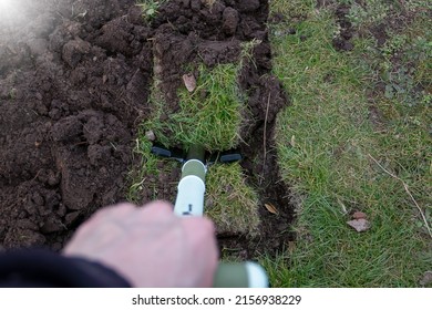 A Closeup Shot Of A Man Holding A Spade Stuck In The Soil With Grass