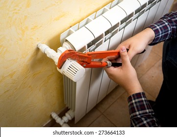 Closeup shot of man installing radiator valve with red plumber pliers