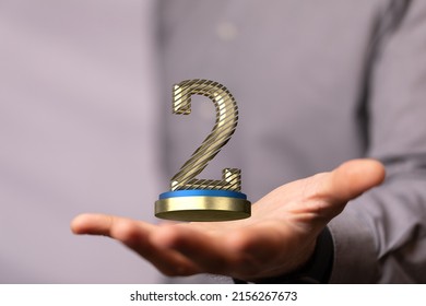 A Closeup Shot Of A Man Showing The 2nd Place Trophy