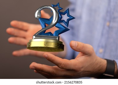 A Closeup Shot Of A Man Showing The 2nd Place Trophy