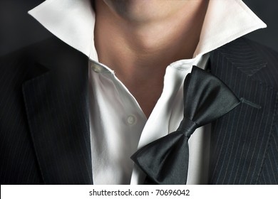 A Close-up Shot Of A Man In A Tux With His Bowtie Hanging And His Collar Undone.