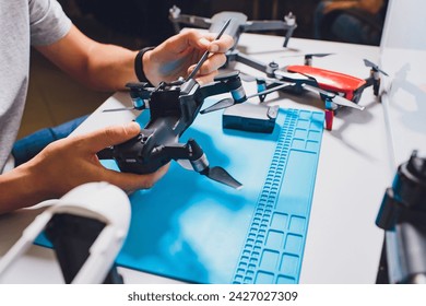 Closeup shot of man working on assembling new surveillance system using quadcopter drone with camera on table with different tools in modern workshop