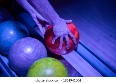 A Closeup Shot Of A Man's Hand Picking Up A Bowling Ball