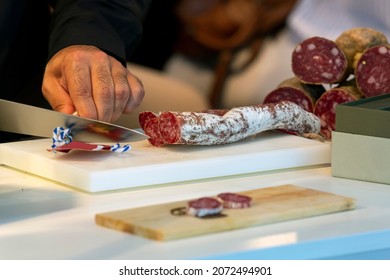 close-up shot of man's hands cutting sausage on a cutting board