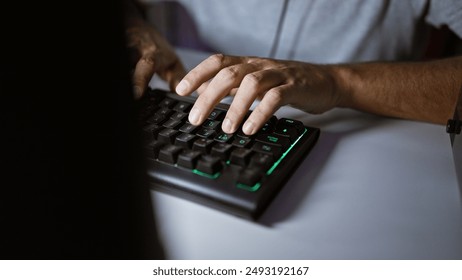 Close-up shot of a man's hands typing on a backlit mechanical keyboard in a dark room. - Powered by Shutterstock