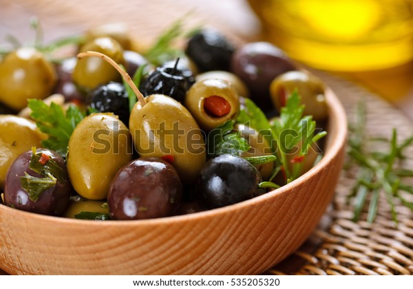 Close-up shot of marinated olives with herbs and
spices in wooden
plate.