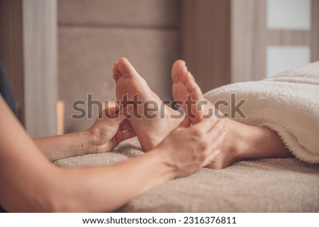 A closeup shot of the masseur's hands massaging the woman's feet.