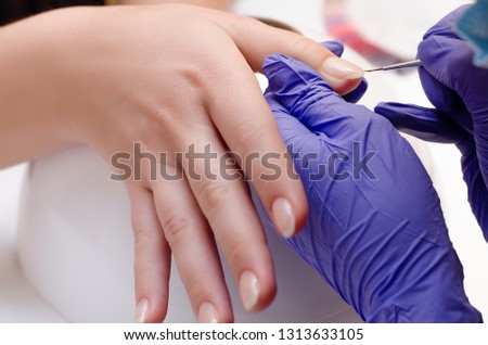 Closeup shot of master in rubber gloves сovering nails with base gel in the beauty salon. Perfect nails manicure process 