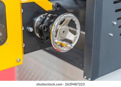 Close-up shot of a metallic, reflective mechanical part with intricate circular and radial design Central component has holes and grooves, emitting light or fluid Surrounded by cylindrical parts wi