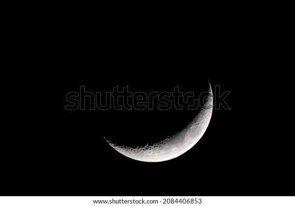 A closeup shot of the Moon crescent in the\
black sky. Moon background.