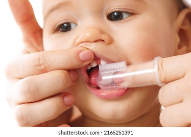 Closeup shot of a mother gently brooshing her small child's teeth with a toothbrush