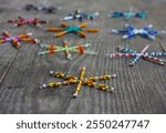 Close-up shot of multicolored decorative stars or Christmas flakes made of wire and beads. A simple Christmas and winter decoration for the Christmas tree on wooden background