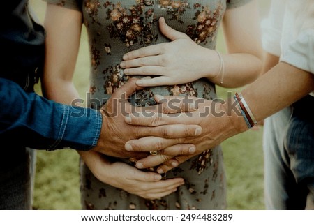 A close-up shot of multiple hands gently resting on a pregnant woman's belly, symbolizing family unity, love, and support during pregnancy