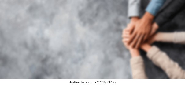 A close-up shot of multiple hands stacked on top of each other, symbolizing teamwork, unity, and shared goals.