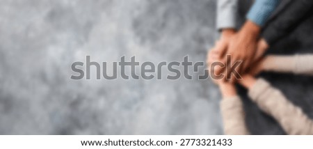 A close-up shot of multiple hands stacked on top of each other, symbolizing teamwork, unity, and shared goals.
