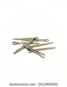 A close-up shot of multiple silver cotter pins scattered on a white background. The cotter pins have a U-shaped design with flared ends and are arranged in a seemingly random pattern.