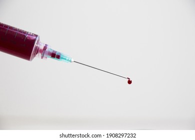 A Closeup Shot Of A Needle Syringe With Blood On The Bevel Isolated On White Background